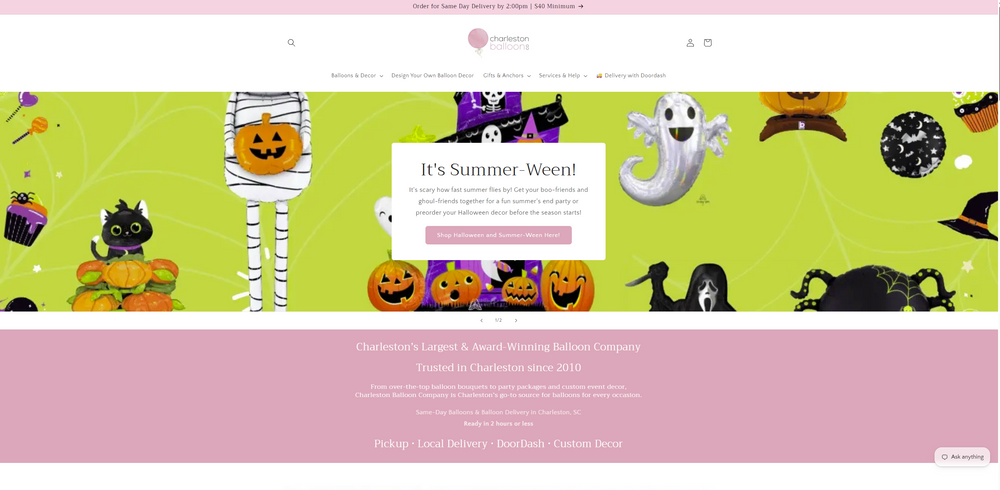 Homepage of Charleston Balloons website. Top pink banner announces “Order for Same Day Delivery by 2:00pm | $40 Minimum.” White header with search icon, circular logo reading “charleston balloons,” and user/cart icons. Navigation links: Balloons & Decor, Design Your Own Balloon Decor, Gifts & Anchors, Services & Help, Delivery with Doordash. Large bright-green Halloween-themed banner featuring cartoon balloon characters (black cats, jack-o’-lanterns, mummy, ghost, spider, witch hat, haunted h